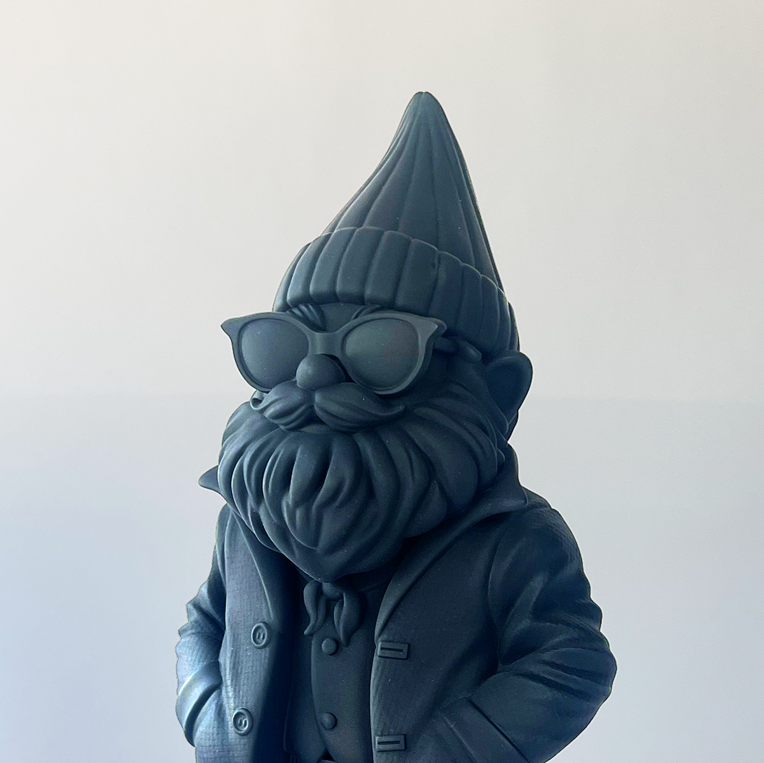 Dark blue gnome figurine with a hat and coat on a light gray background
